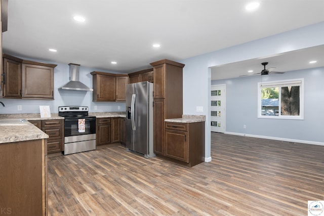 kitchen with recessed lighting, appliances with stainless steel finishes, dark wood-type flooring, a sink, and wall chimney exhaust hood