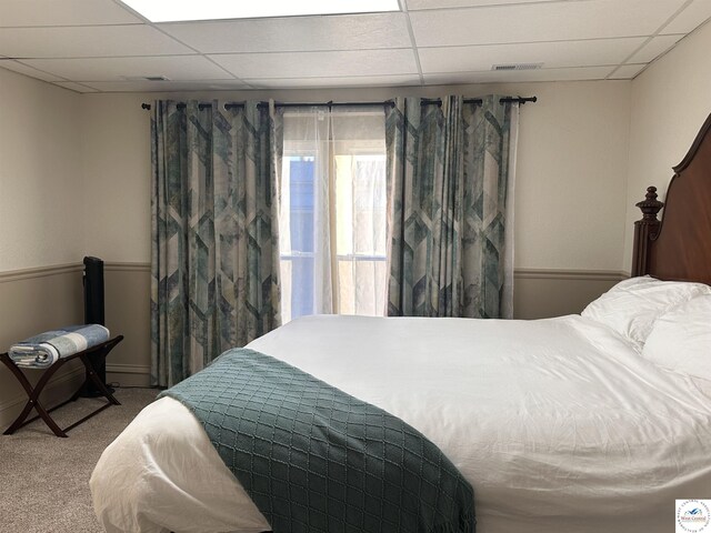 carpeted bedroom with a drop ceiling and visible vents