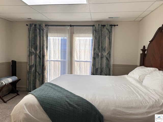 carpeted bedroom with a drop ceiling and visible vents