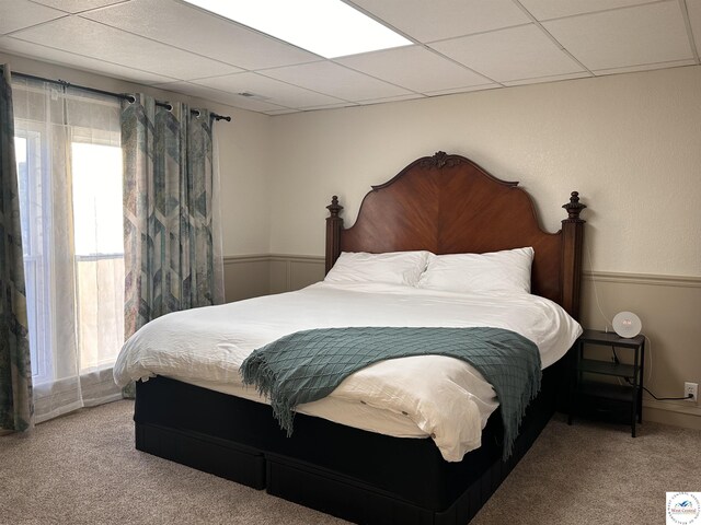 bedroom with a paneled ceiling, multiple windows, carpet floors, and a wainscoted wall