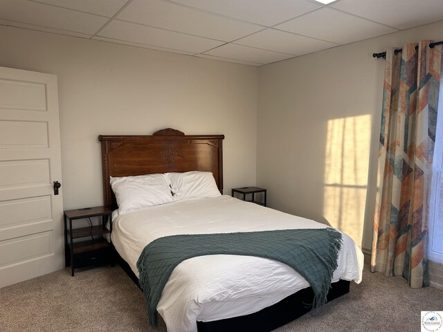 carpeted bedroom featuring a drop ceiling