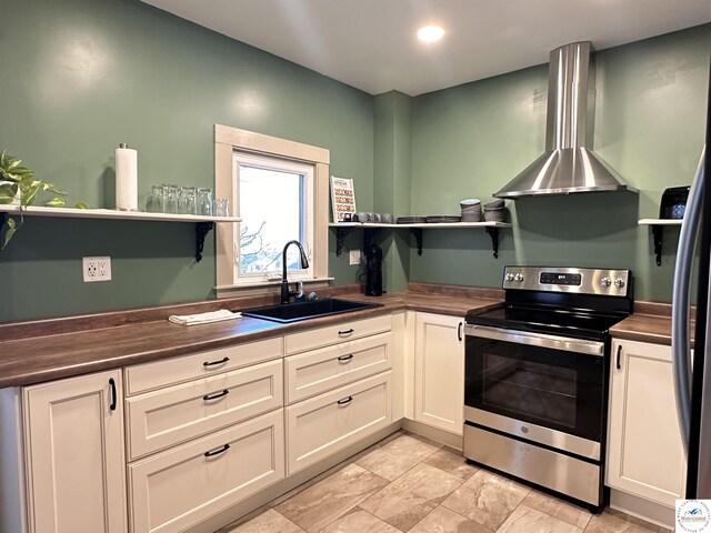 kitchen featuring stainless steel electric stove, a sink, wall chimney exhaust hood, and open shelves