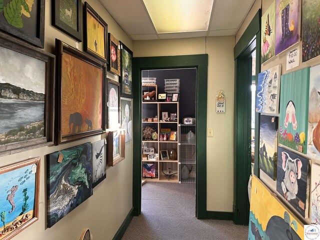 corridor featuring baseboards and carpet