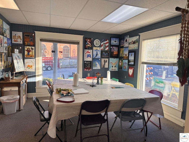 carpeted dining area with a drop ceiling