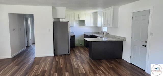 kitchen featuring a sink, baseboards, white cabinets, freestanding refrigerator, and dark wood-style floors