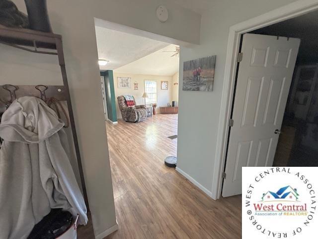 hallway with vaulted ceiling, wood finished floors, and baseboards