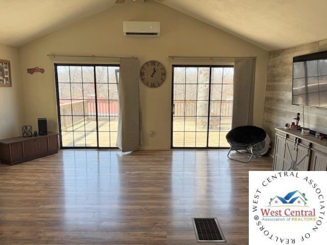 unfurnished living room featuring a wall unit AC, plenty of natural light, and lofted ceiling