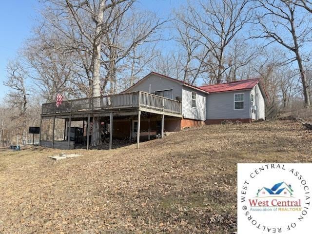 back of house with a wooden deck and metal roof