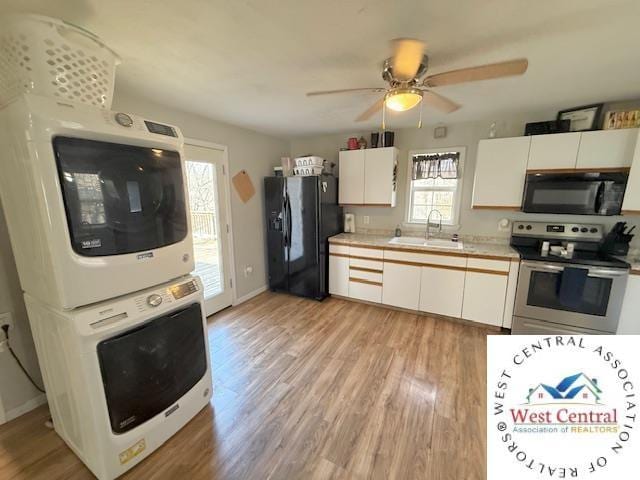 kitchen with a wealth of natural light, black appliances, stacked washing maching and dryer, and a sink