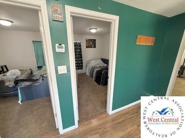 hall with wood finished floors, baseboards, and carpet floors