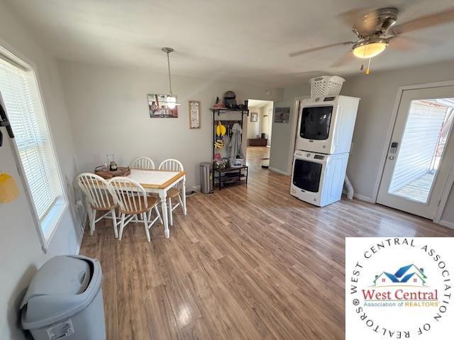 dining area featuring plenty of natural light, light wood-type flooring, a ceiling fan, and stacked washer and dryer