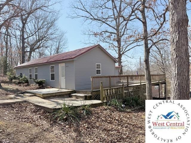 rear view of property featuring metal roof and a wooden deck