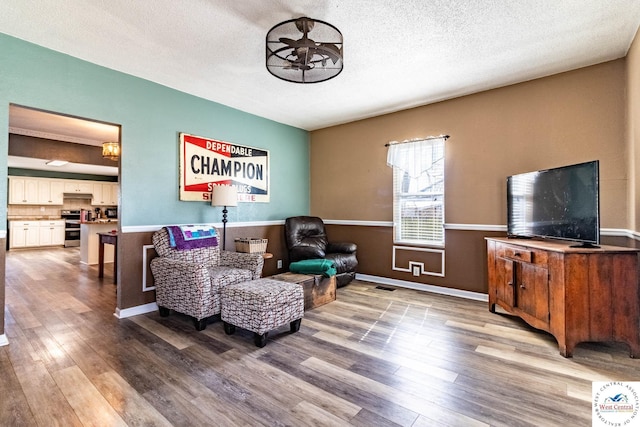 living area featuring a textured ceiling, visible vents, and wood finished floors