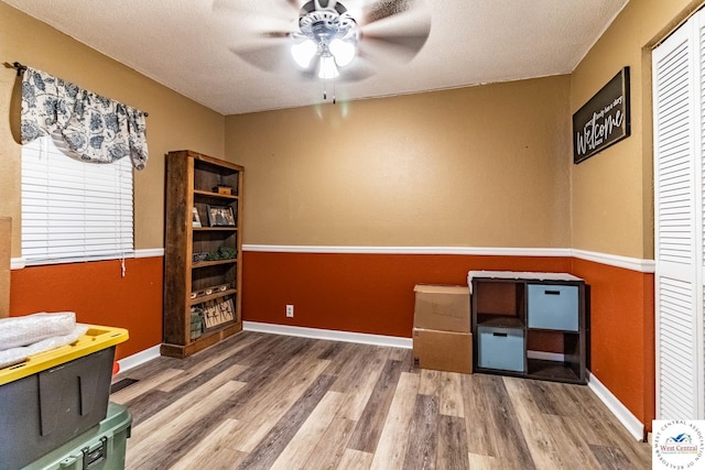 office featuring dark wood-style floors, a textured ceiling, a ceiling fan, and baseboards