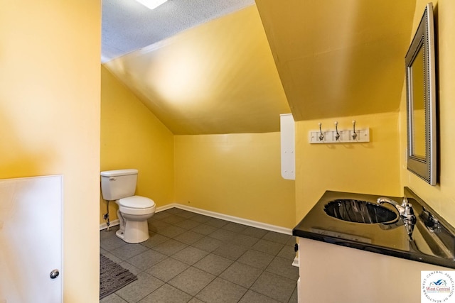 bathroom featuring lofted ceiling, toilet, vanity, baseboards, and tile patterned floors