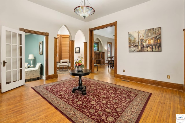 interior space featuring arched walkways, wood finished floors, visible vents, and baseboards