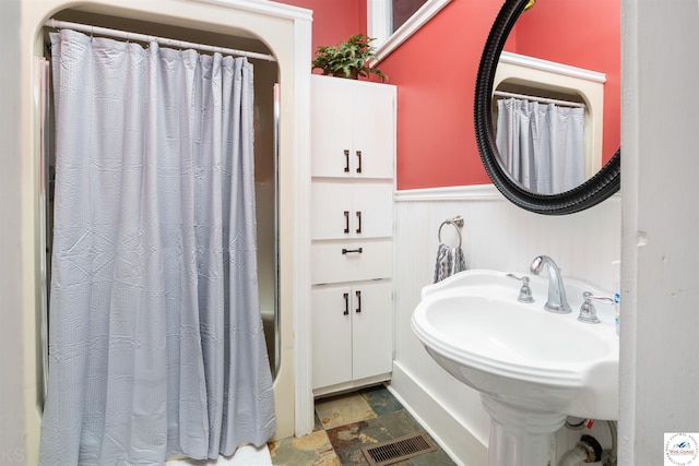 full bathroom with a sink, visible vents, wainscoting, a shower with curtain, and stone finish floor