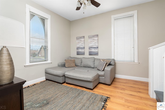 living room featuring ceiling fan, baseboards, and wood finished floors