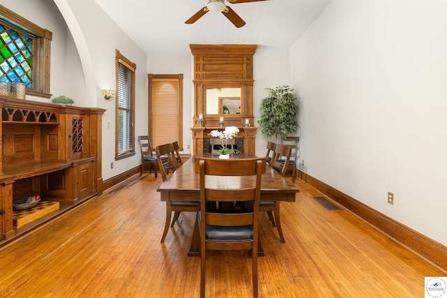 dining room featuring light wood-style floors, baseboards, visible vents, and a ceiling fan