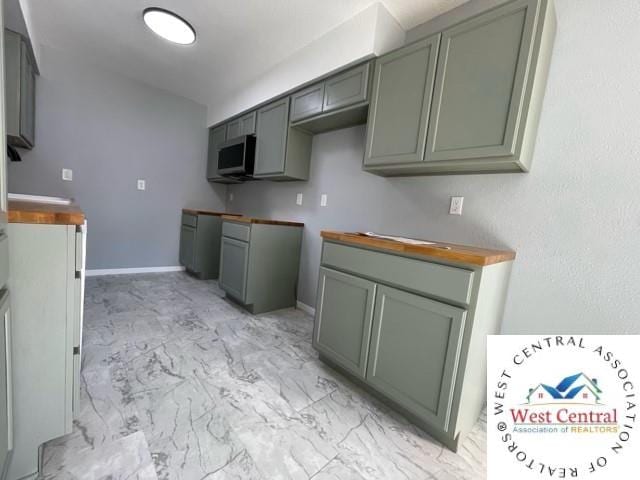 kitchen with marble finish floor, baseboards, and stainless steel microwave