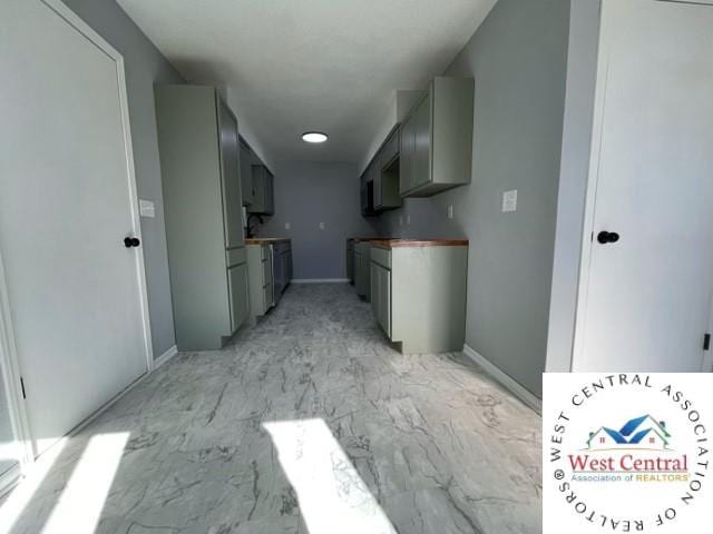 kitchen featuring marble finish floor, baseboards, and gray cabinetry