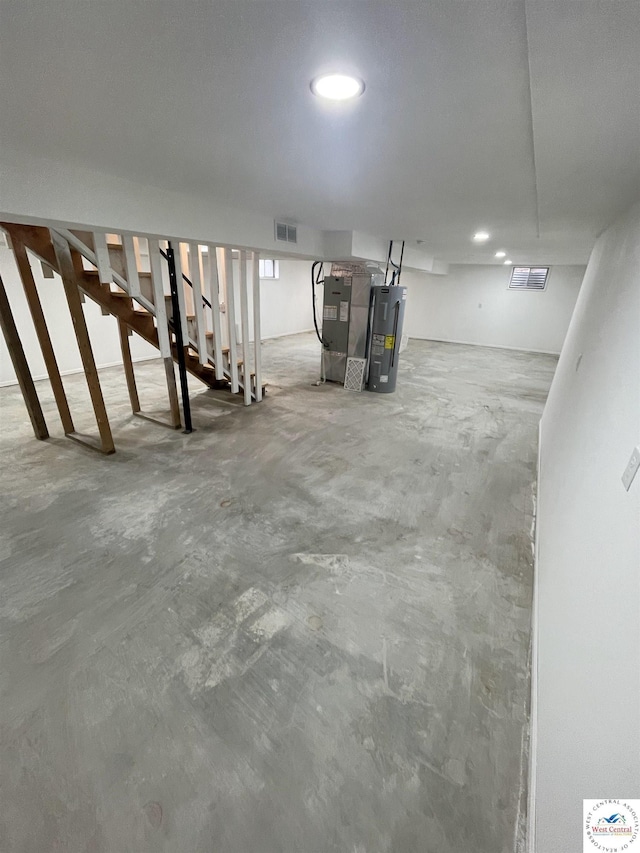 unfinished basement with electric water heater, visible vents, and heating unit