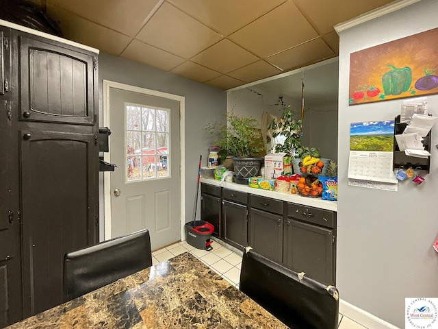 kitchen with light countertops, a drop ceiling, and light tile patterned floors