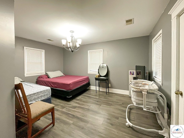 bedroom featuring baseboards, visible vents, an inviting chandelier, and wood finished floors