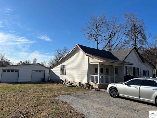 view of home's exterior with covered porch, a yard, a detached garage, and an outbuilding