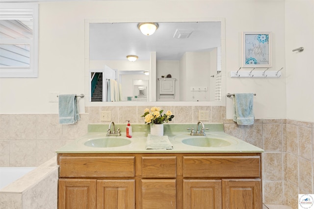 bathroom with visible vents, a sink, a bath, and double vanity