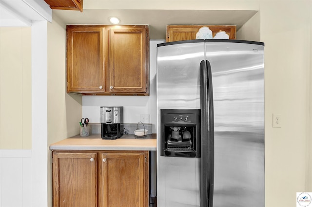 kitchen featuring brown cabinetry, light countertops, and stainless steel refrigerator with ice dispenser