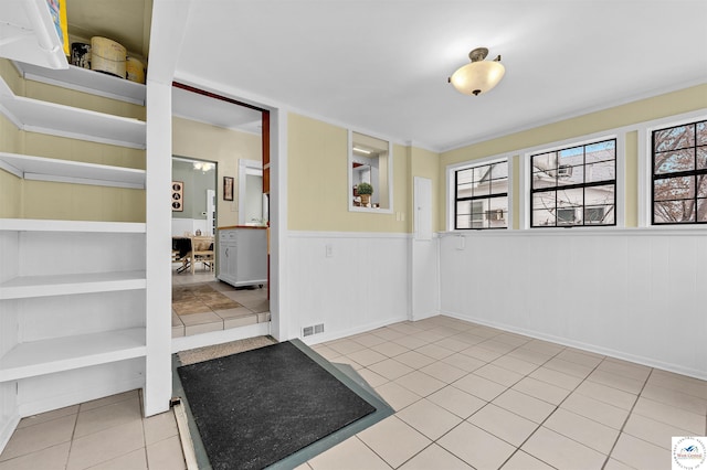 interior space featuring tile patterned flooring, a wainscoted wall, and visible vents