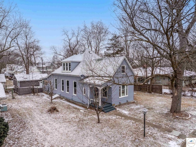 snow covered rear of property featuring a residential view and fence