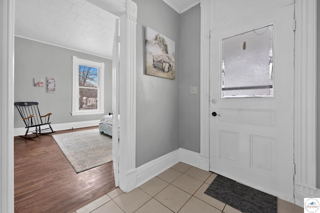 doorway featuring baseboards, crown molding, and light tile patterned flooring