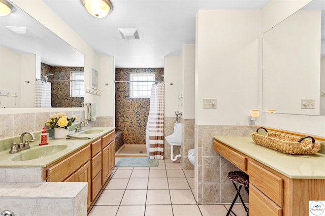 bathroom with a stall shower, tile walls, a sink, and tile patterned floors