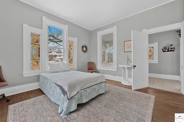 bedroom with baseboards, wood finished floors, and ornamental molding