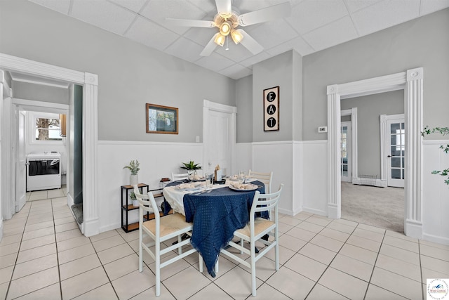 dining area with light tile patterned floors, a wealth of natural light, a paneled ceiling, washer / clothes dryer, and wainscoting