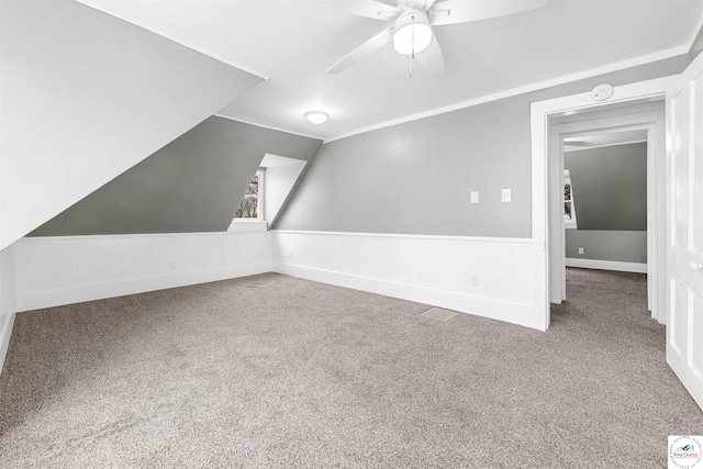 bonus room featuring wainscoting, carpet flooring, vaulted ceiling, and ceiling fan