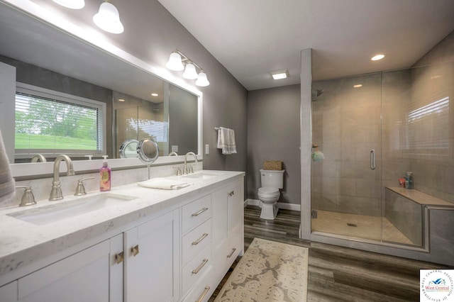 bathroom with toilet, double vanity, a sink, and wood finished floors