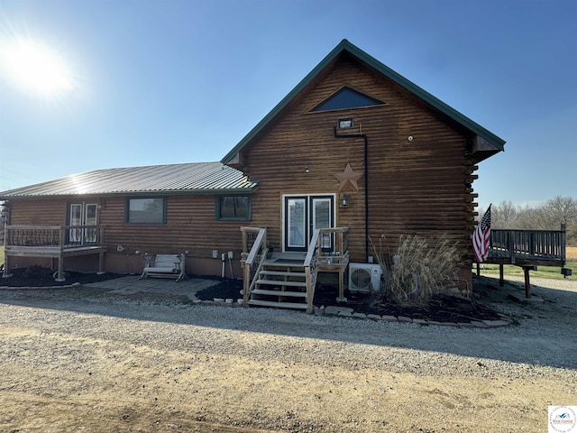 rear view of house with a standing seam roof, metal roof, log exterior, and ac unit