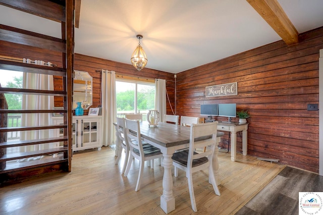 dining area featuring wood walls, a chandelier, wood finished floors, and beamed ceiling