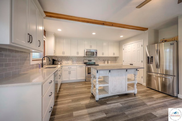 kitchen featuring appliances with stainless steel finishes, a center island, white cabinetry, open shelves, and a sink