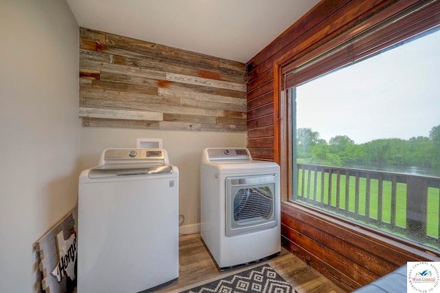 clothes washing area with laundry area, separate washer and dryer, light wood-style floors, and wood walls