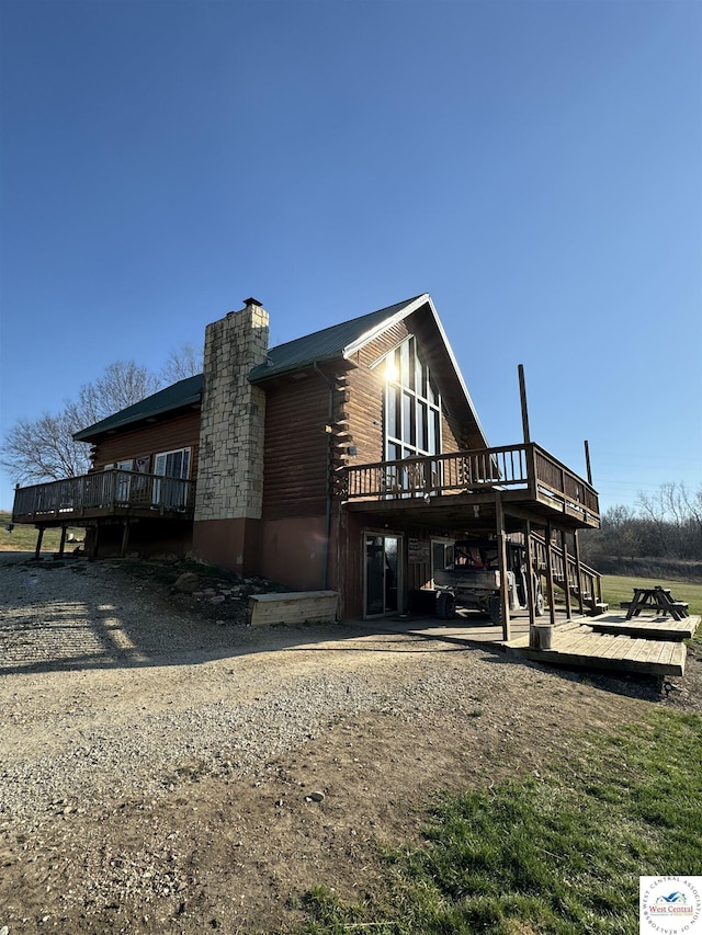 view of side of home featuring stairway, a chimney, and a wooden deck