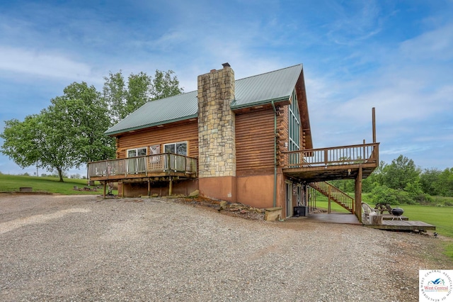 view of property exterior featuring log exterior, metal roof, a chimney, and a wooden deck