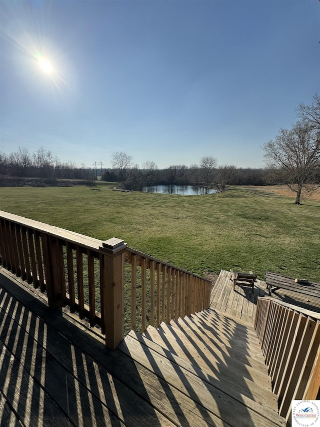 deck featuring a water view, a yard, and a rural view