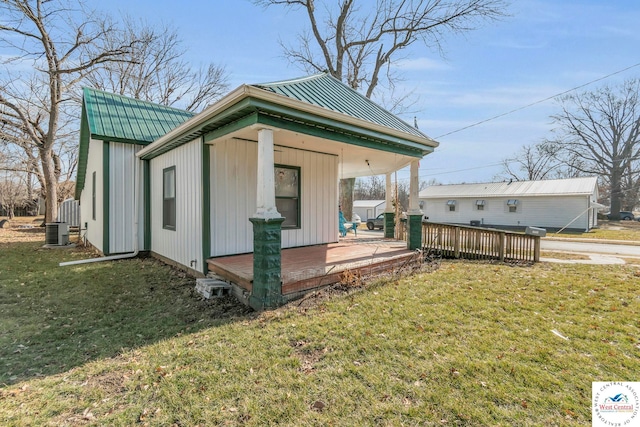 exterior space featuring metal roof, central AC, an outdoor structure, a lawn, and a wooden deck