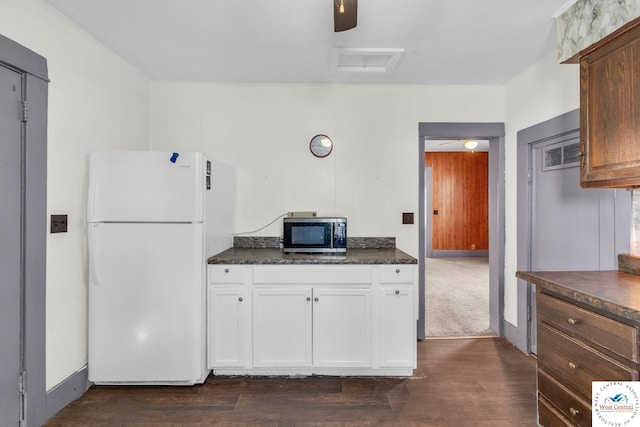 kitchen with baseboards, dark wood-style floors, stainless steel microwave, freestanding refrigerator, and white cabinetry