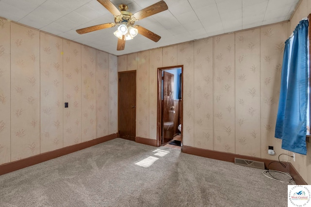 carpeted empty room with baseboards, ceiling fan, visible vents, and wallpapered walls