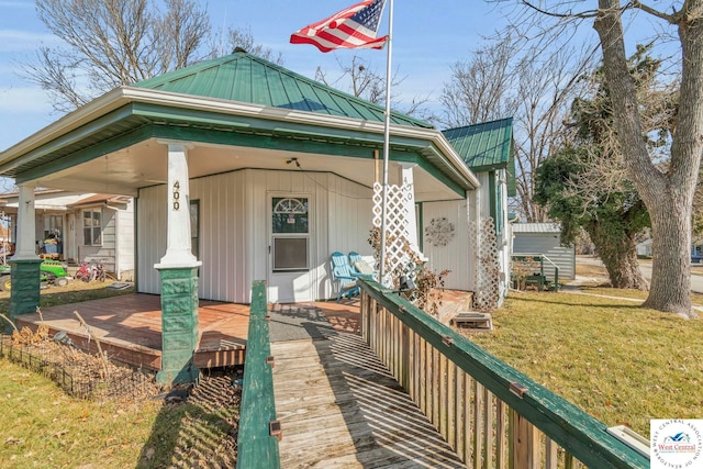 view of front of property with covered porch, metal roof, a front lawn, and a standing seam roof